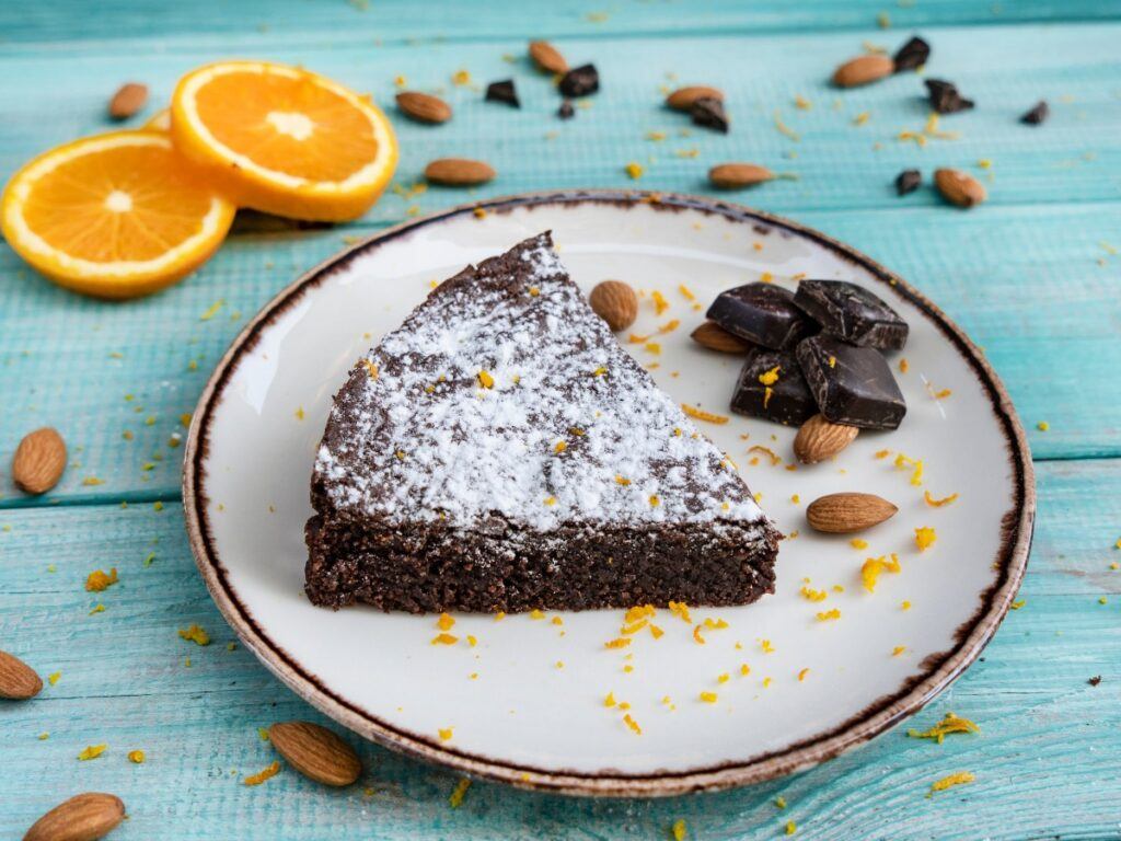 Chocolate cake dusted with confectioners sugar. Blue background with orange garnish