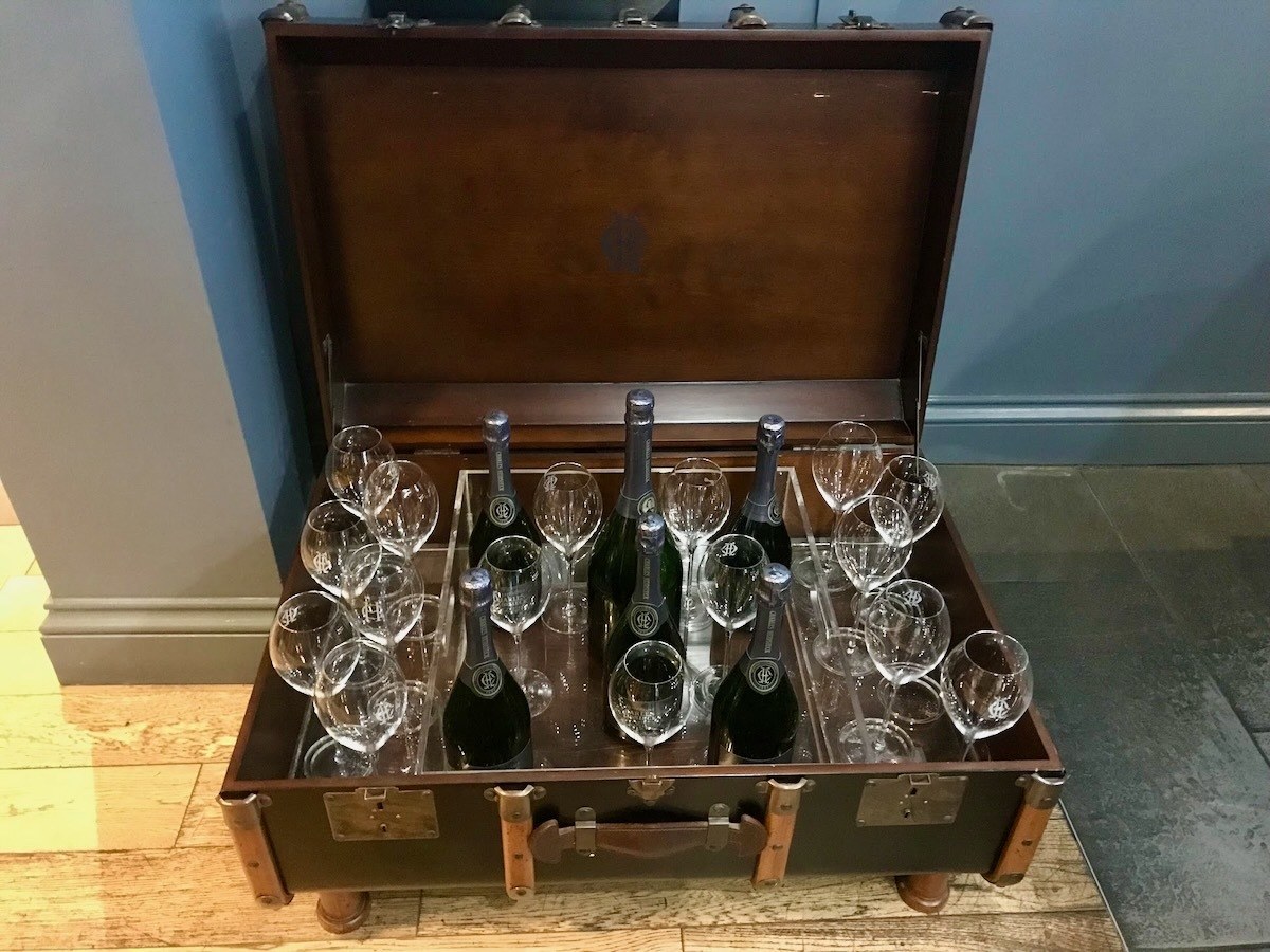 Old suitcase filled with wine bottles and glasses.
